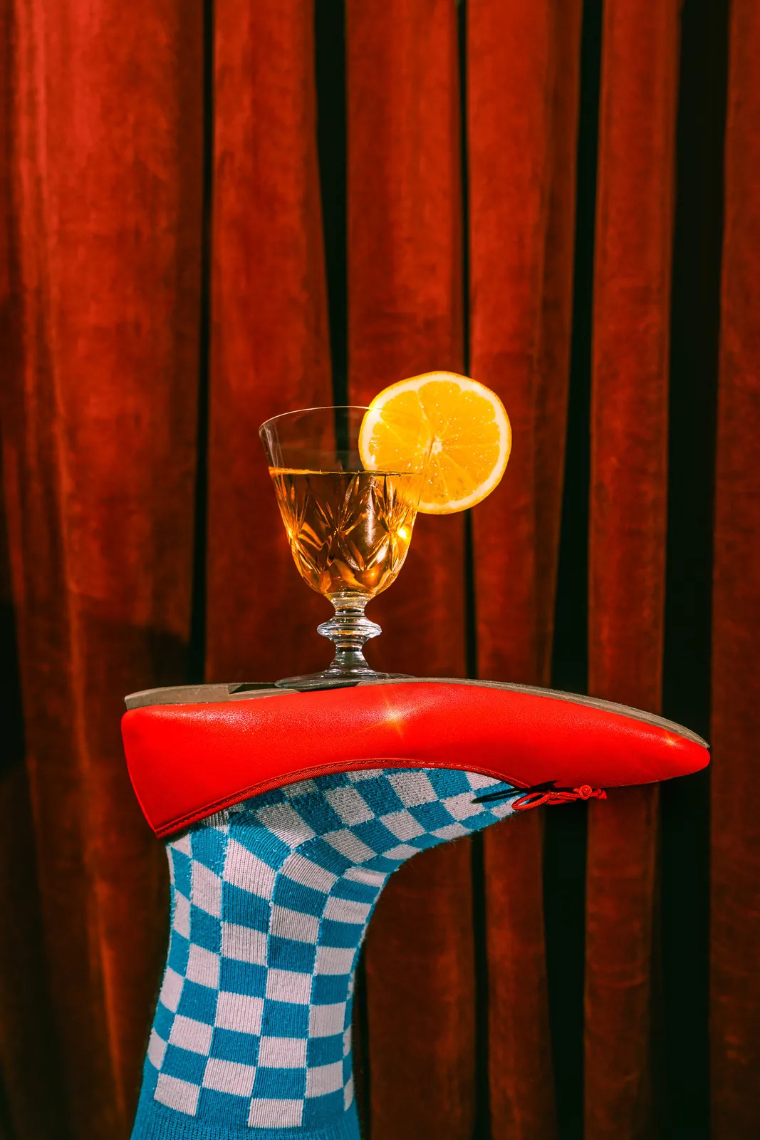 A red shoe balancing a glass with a lemon slice