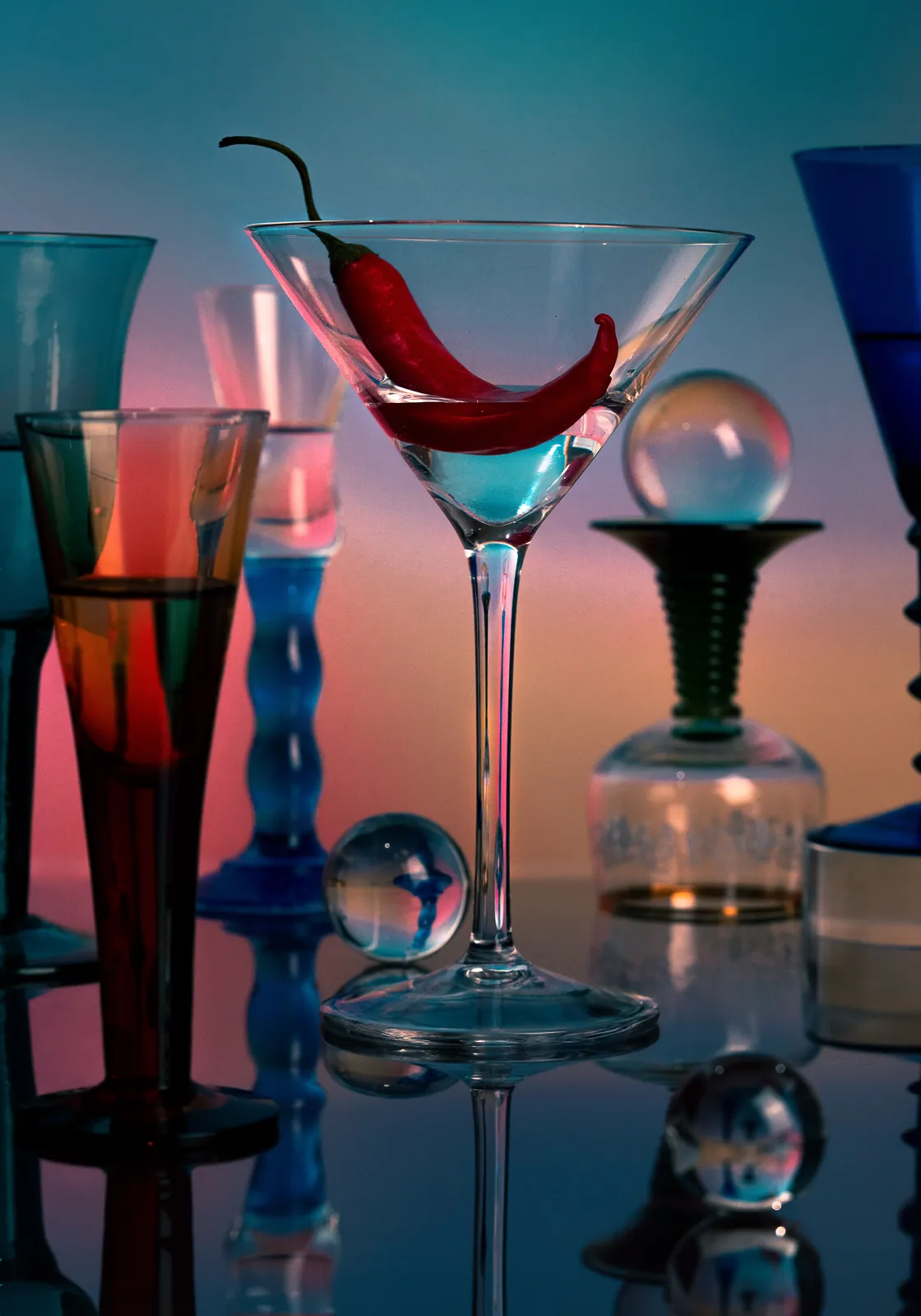 A chilli in a martini glass among coloured glassware