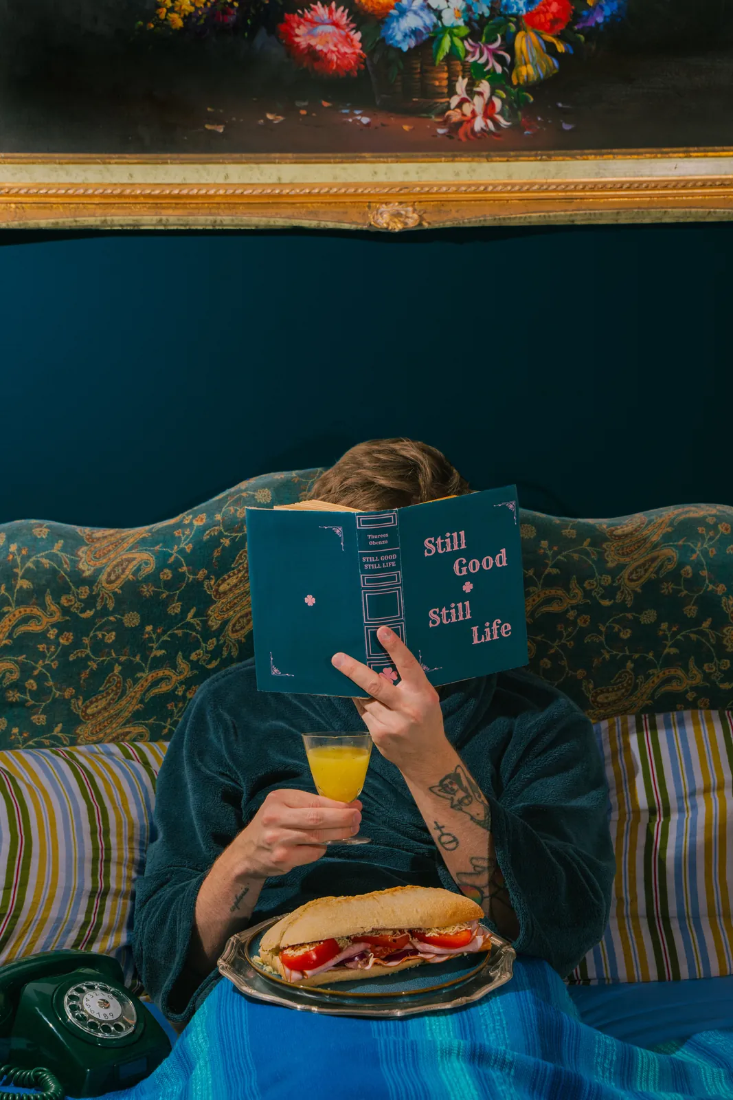A reader with a Still Good, Still Life book, juice and a sandwich