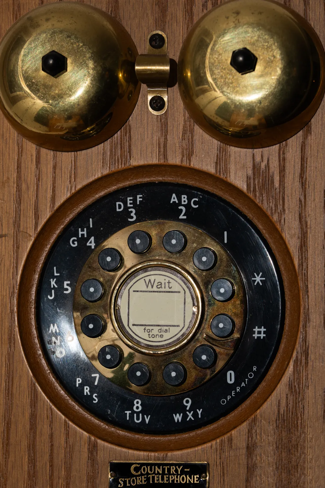 A vintage wall telephone dial in brass and wood