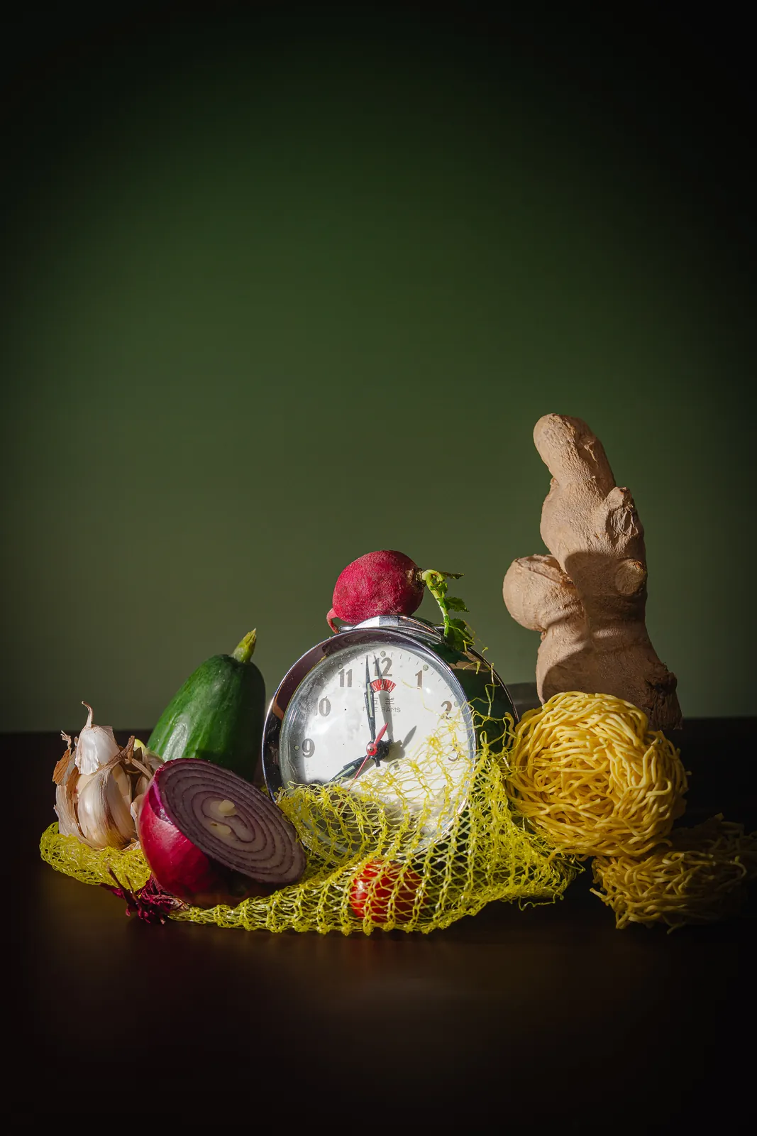 Vegetables, a clock, and a mesh bag in a dark still life