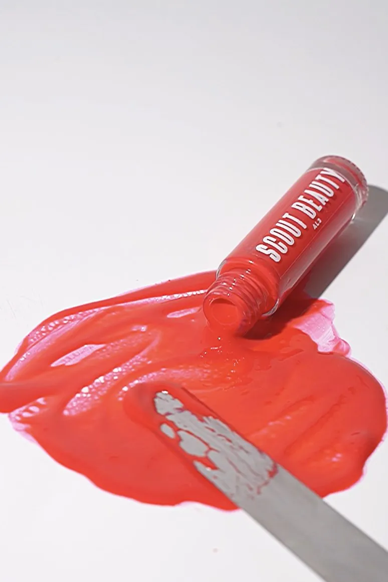 A palette knife dragging through a pool of red Scout Beauty gloss
