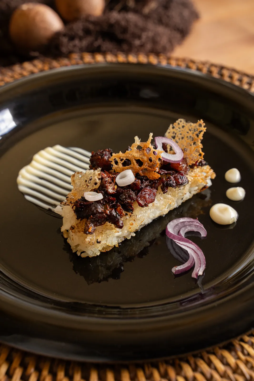 Sisig on a crispy rice cake with a lace tuile