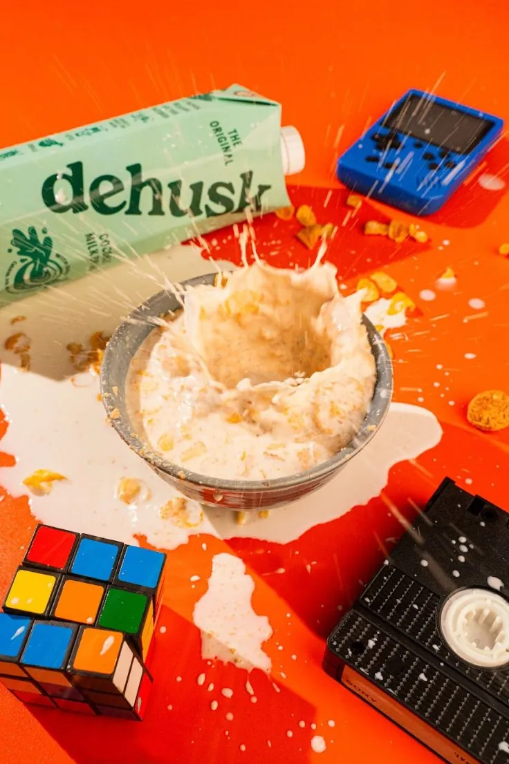 Dehusk cereal splashing out of a bowl beside a Rubik's cube