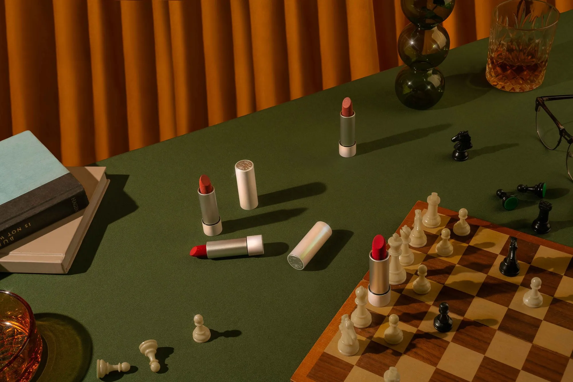 Lipsticks among chess pieces on a green felt table