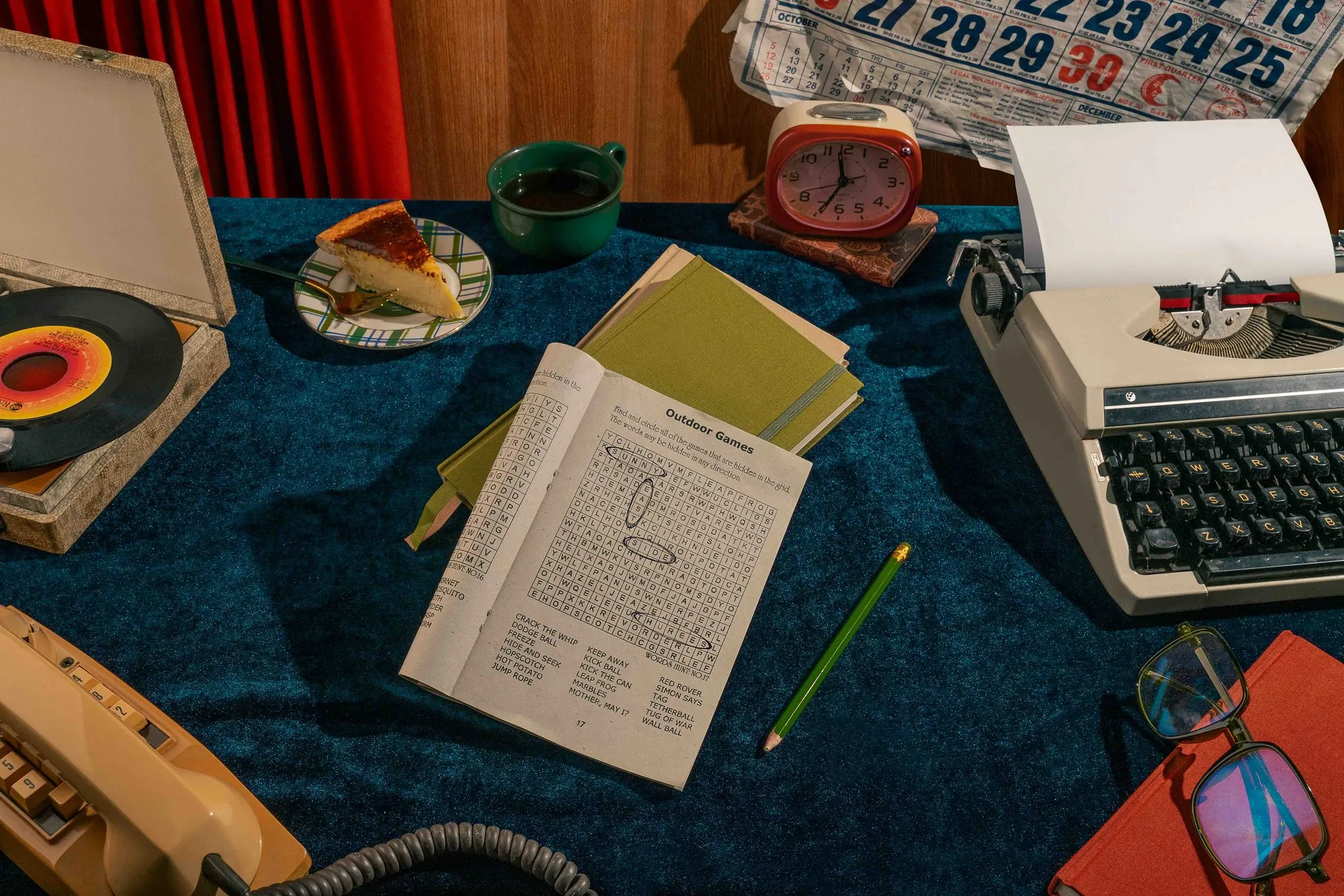 A crossword, typewriter, and record player on a blue cloth