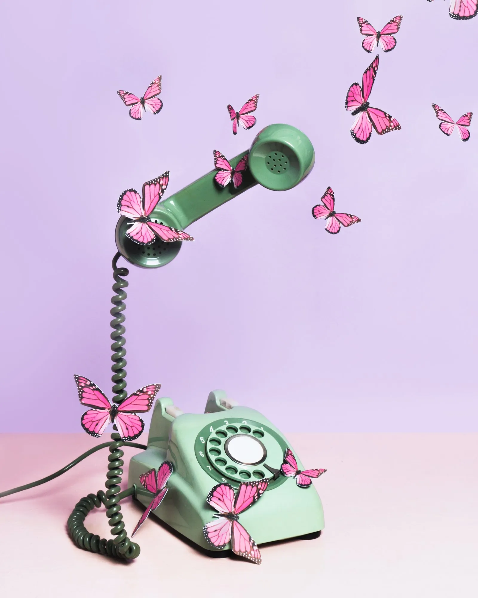 A mint rotary phone wrapped in paper butterflies on lilac