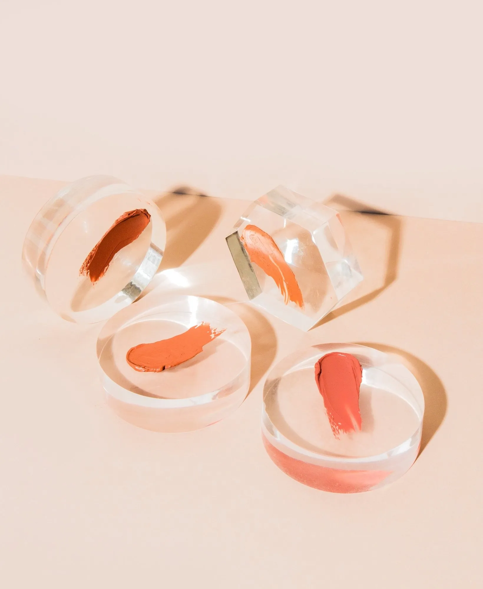 Lipstick samples in clear dishes on blush